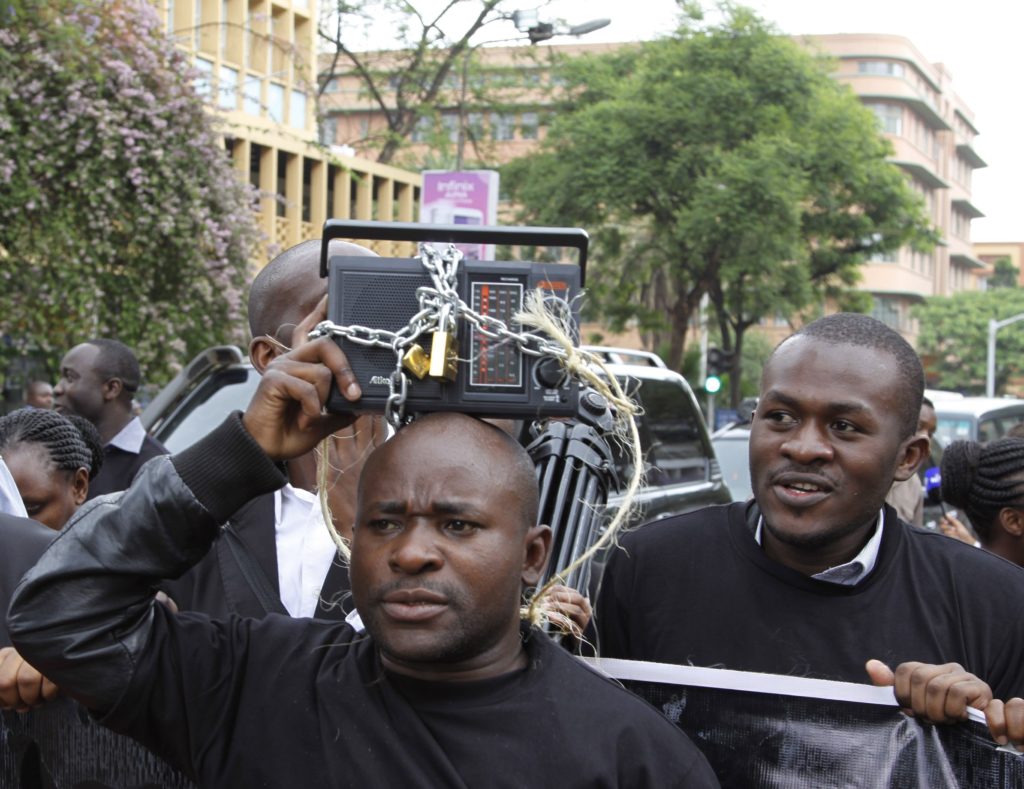 Kenyan journalists display a symbolically locked radio, during a protest against the Media Bill in Nairobi, Kenya, Tuesday, Dec. 3, 2013. A media protest was called on by various media houses to protest new draconian laws that are being tabled by parliament. (AP Photo/Khalil Senosi)